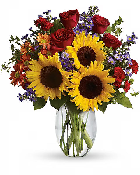 Bouquet of sunflowers and red roses in a clear vase