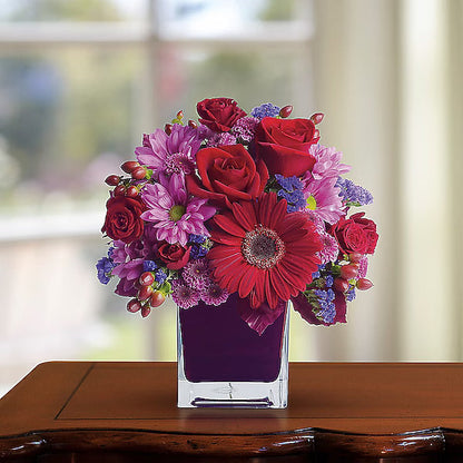 Vibrant flowers arranged in a glass vase with a soft background.