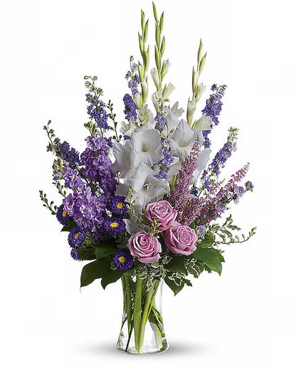 Elegant glass vase holding purple and white flower arrangement on white background