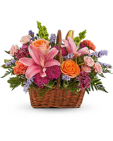 Floral arrangement in a basket with pink lilies, orange roses, and other flowers on a white background